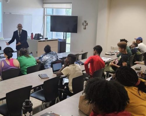 The Academy for Scholastic and Personal Success 2023 Summer Session. Students listening to Eric M. Thompson, ASPS Assistant Director